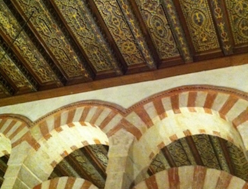 Ceiling and arches inside a place of worship that demonstrate Christian and Moorish styles.