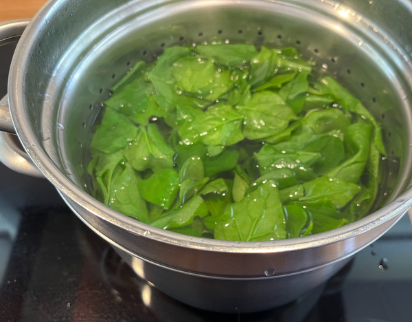 Warrigal Greens being cooked in boiling water in a large saucepan.